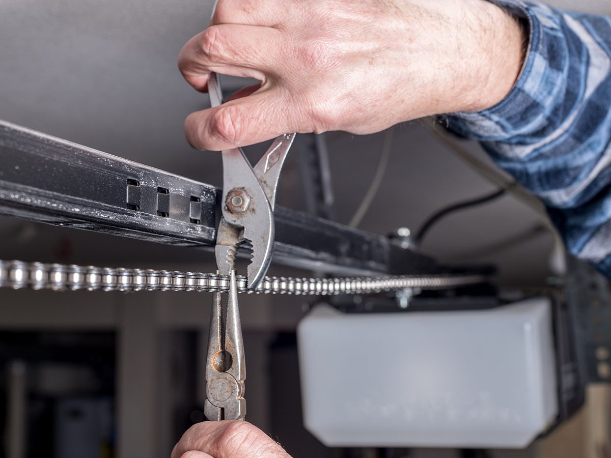 man working on garage door chain with pliers
