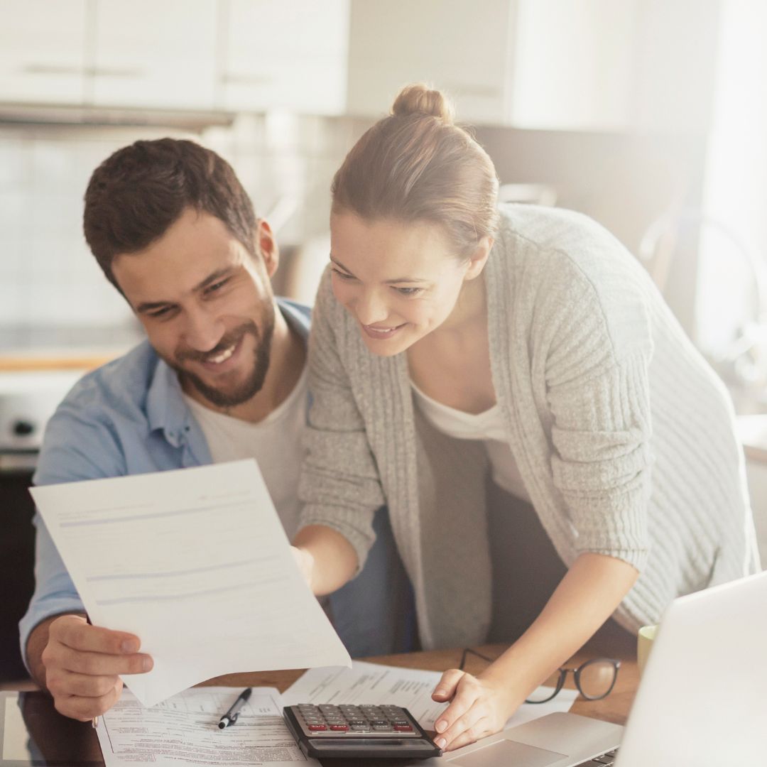 a happy couple looking at paperwork together with a calculator
