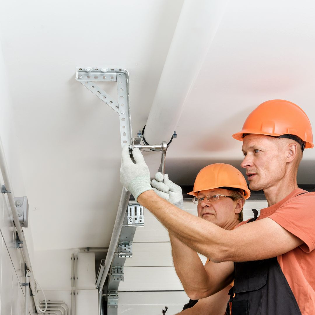 Two garage door repair men work on garage door